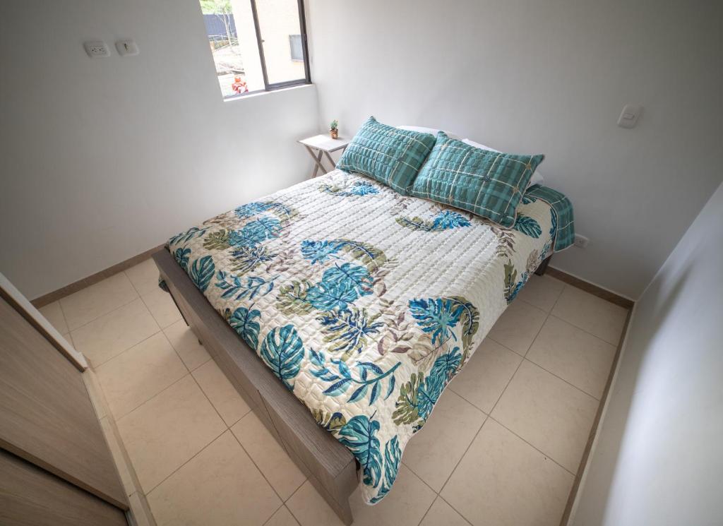 a bedroom with a bed with a quilt and pillows at Apartamento cómodo, luz natural, zonas comunes, piscinas traer gorro, wifi, parqueadero en el Quindío in La Tebaida