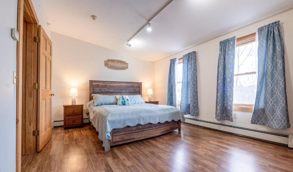 a bedroom with a bed and two windows at Downtown Apartments in Bar Harbor in Bar Harbor