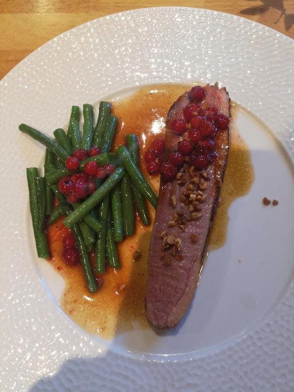 a plate of food with a piece of meat and green beans at Logis Hôtel-Restaurant Les Airelles in Neufchâtel-en-Bray