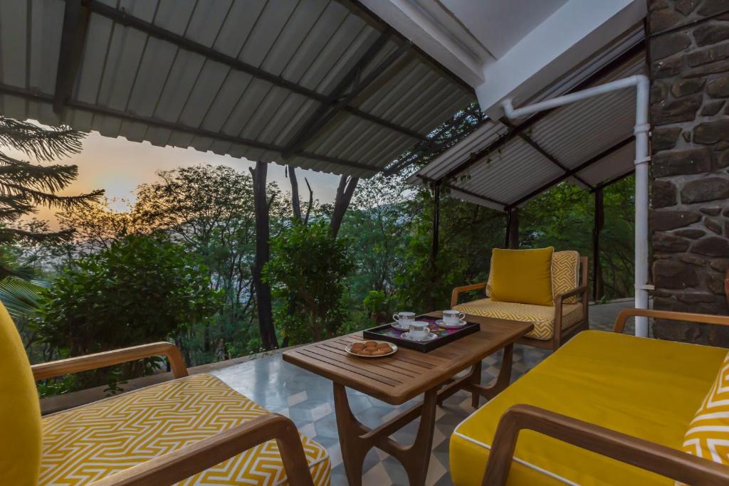 eine abgeschirmte Veranda mit einem Tisch und Stühlen in der Unterkunft SaffronStays Inverlochy, Lonavala in Kārli