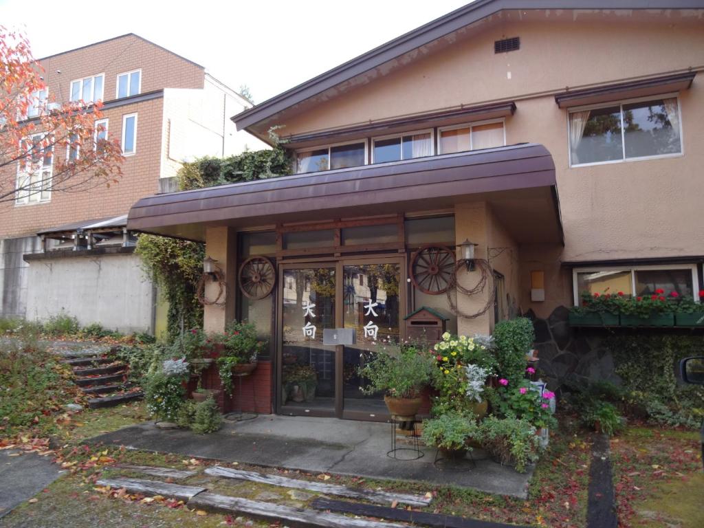 a house with a front door with flowers and plants at Oomukou Ryokan in Hakuba