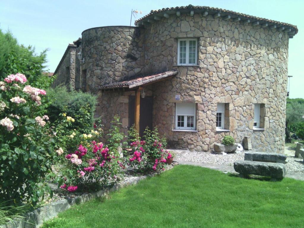 a stone house with flowers in front of it at CASA SEBASTIANA SUITE in Losar de la Vera