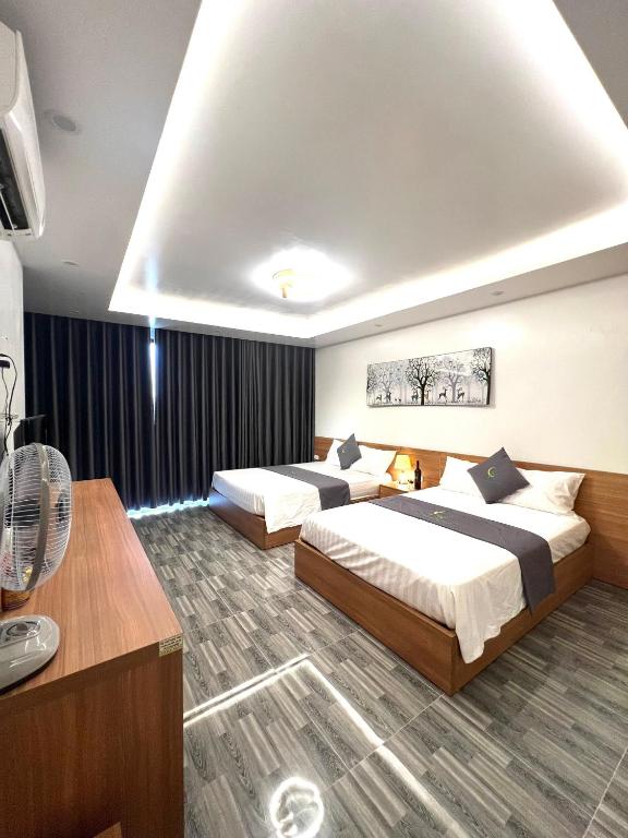 a hotel room with two beds and a fan at An Cường Hotel in Sầm Sơn