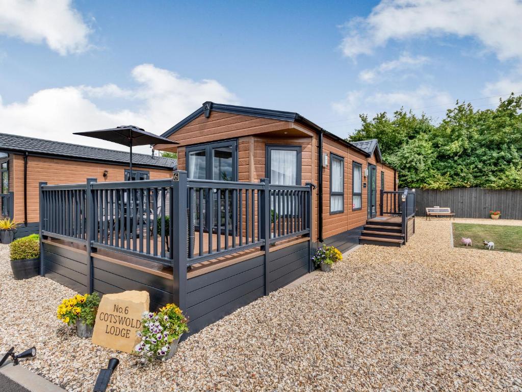 a log cabin with a deck and an umbrella at The Cotswold Holiday Lodge in Evesham