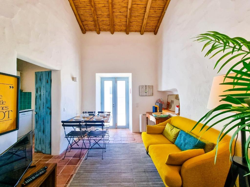 a living room with a yellow couch and a table at FLH Vale Judeu Rustic Mezzanine Cottage I in Loulé