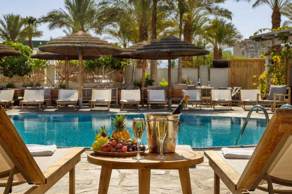 einen Tisch mit einer Obstschale neben einem Pool in der Unterkunft Play Eilat Hotel in Eilat