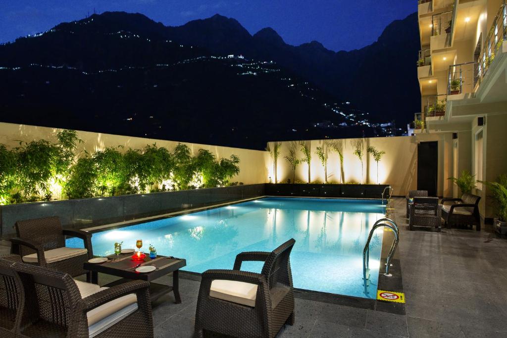 a swimming pool at night with chairs and a table at Ramada by Wyndham Katra Station Road in Katra