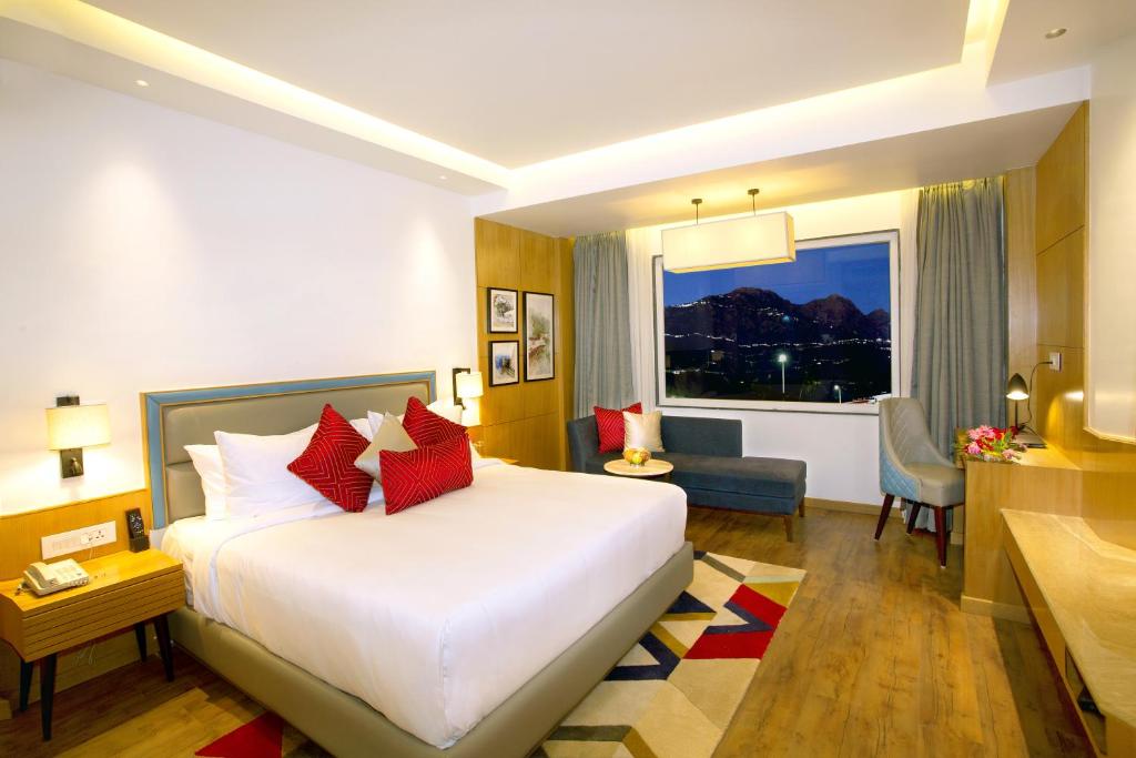 a hotel room with a bed and a window at Ramada by Wyndham Katra Station Road in Katra