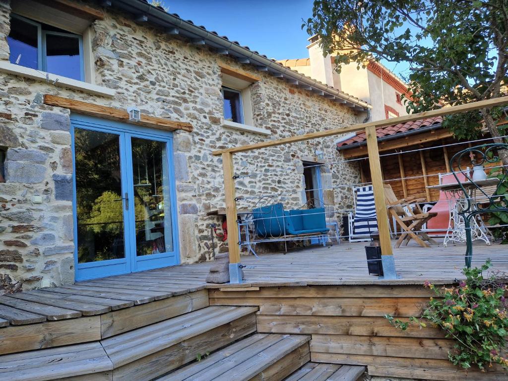 a stone house with a wooden porch and a patio at La maison du vigneron in Auzon
