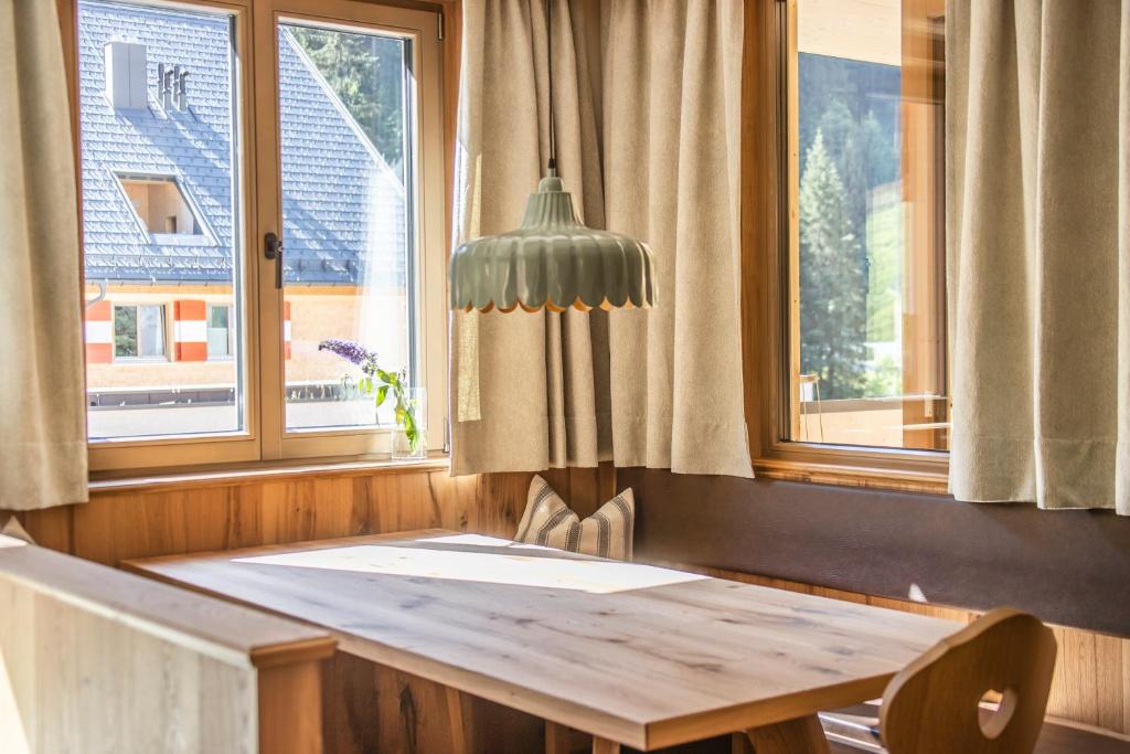 a dining room with a table and two windows at Berghaus Schröcken - Hotel Apartments Spa in Schröcken