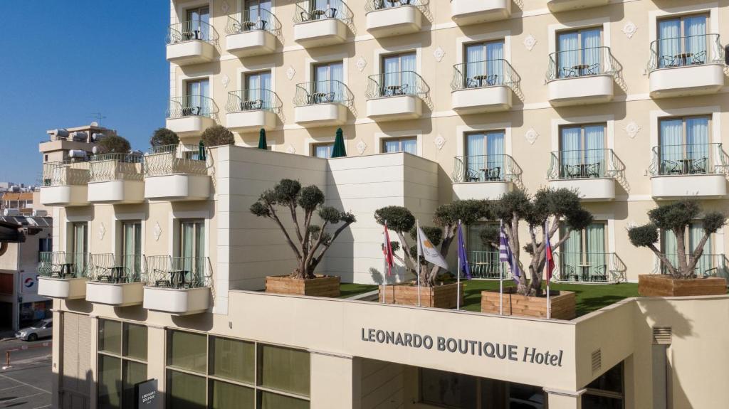 um hotel com vasos de árvores na fachada em Leonardo Boutique Hotel Larnaca em Lárnaca