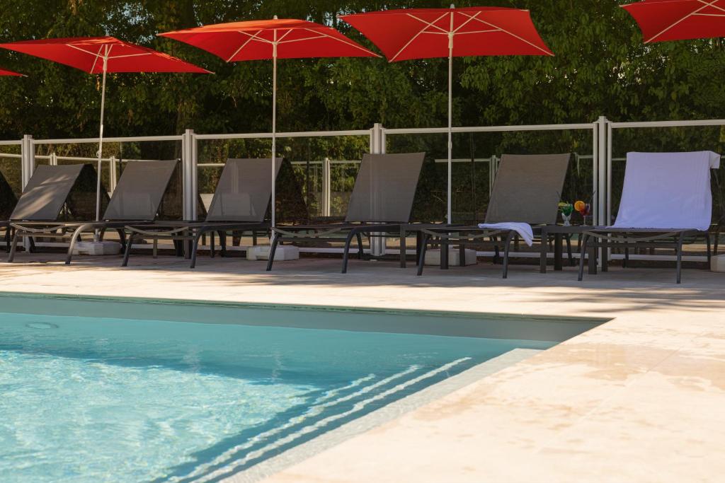 a group of tables and chairs with umbrellas next to a pool at ibis Lyon Nord in Dardilly