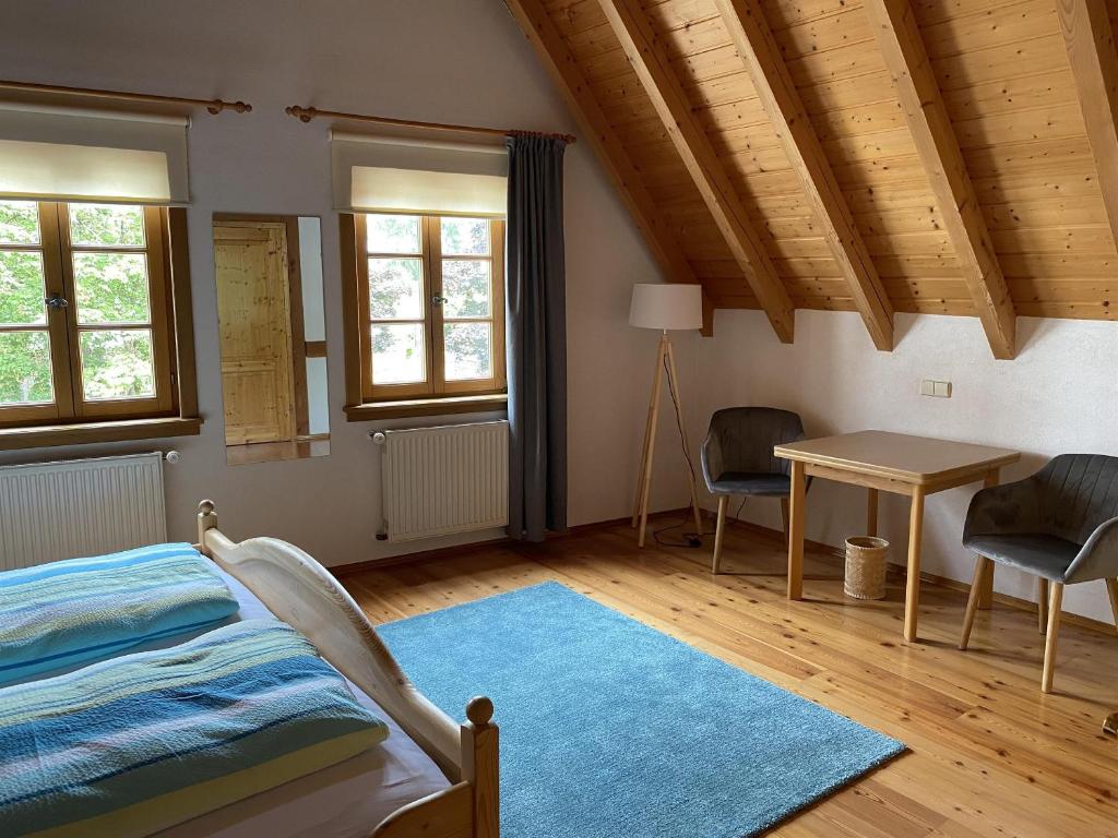 a bedroom with a bed and a desk and windows at Gästehaus Winzerhof Bader in Heuchelheim-Klingen