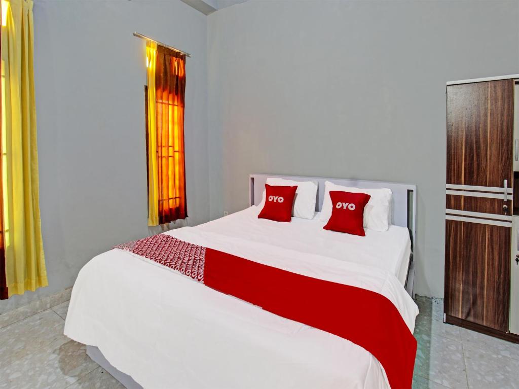 a bedroom with a large white bed with red pillows at OYO 91210 Hotel J3 in Lombok