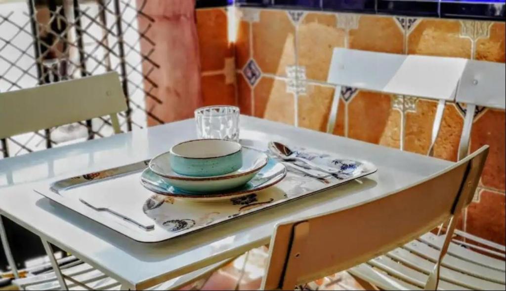 Biały stół z talerzem i naczyniami. w obiekcie Typical Sevillan 2 bedroom unit w Sewilli