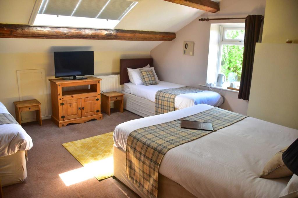 a hotel room with two beds and a television at Robin Hood Inn in Hebden Bridge