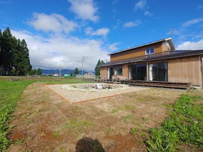 a house in a field next to a building at Guest House Inawashiro~Hanbog~ in Inawashiro