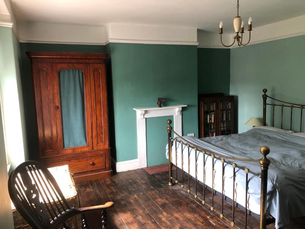 a bedroom with green walls and a bed and a chair at The Victorian House in Bridport