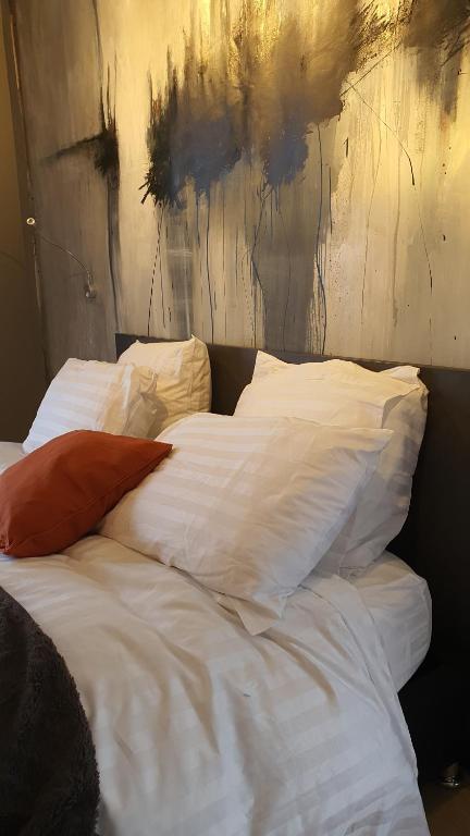een bed met witte lakens en kussens in een slaapkamer bij gîte Artbnb in Armbouts-Cappel