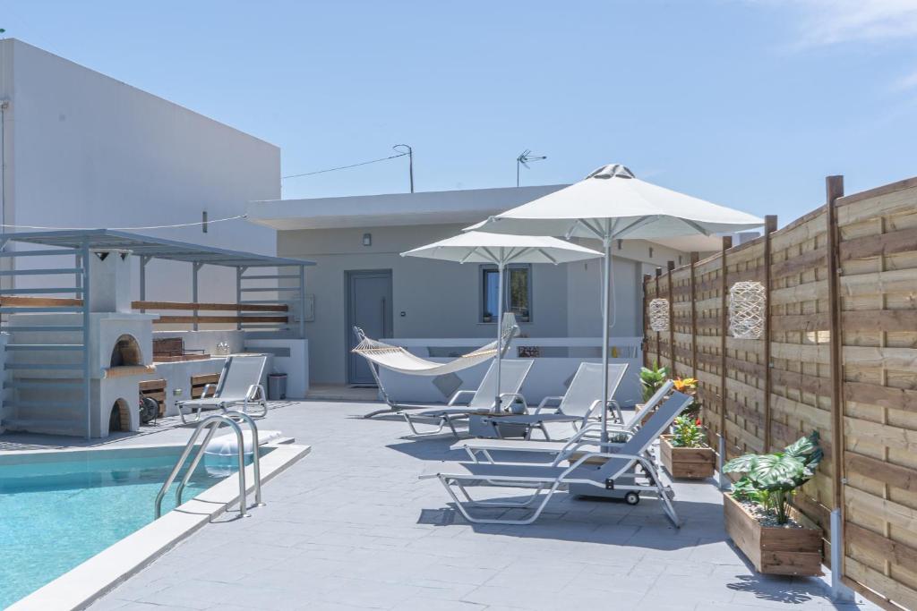 a patio with chairs and an umbrella and a pool at Villa Bella Gonia in Gonia