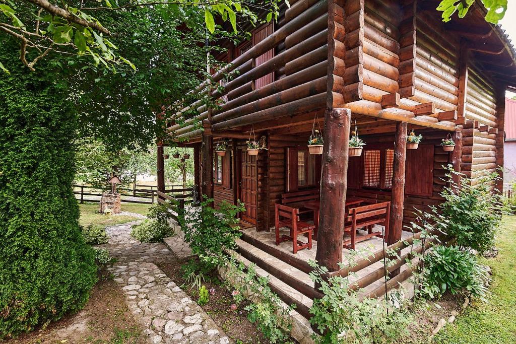 a wooden cabin with chairs and a porch in front of it at Country House Brijest in Kolašin