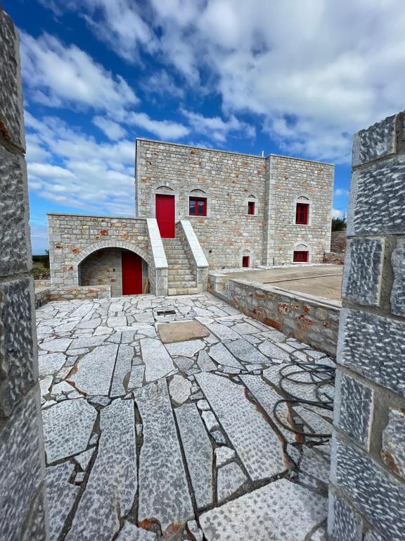 een stenen gebouw met rode deuren en een stenen vloer bij Sugar Stone House 2 in Pirgos Dhirou