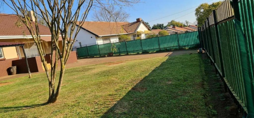 a fence in front of a yard with a tree at Waltershort Guest House and Bed and Breakfast in Pietermaritzburg