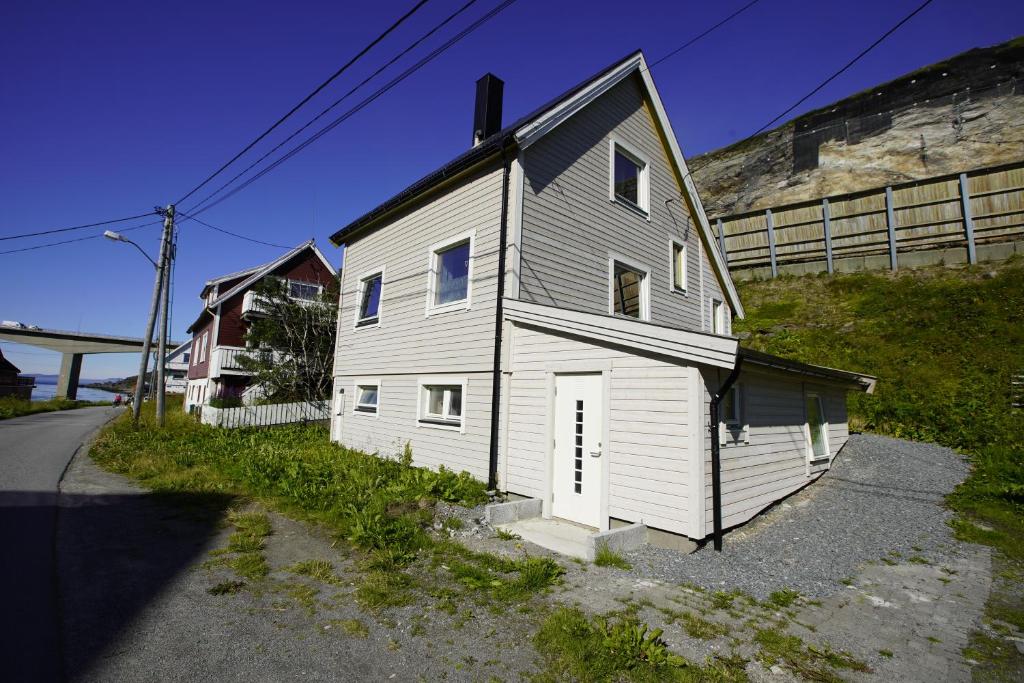 een klein wit huis aan de kant van een weg bij Cosy House Strangata in Måsøy