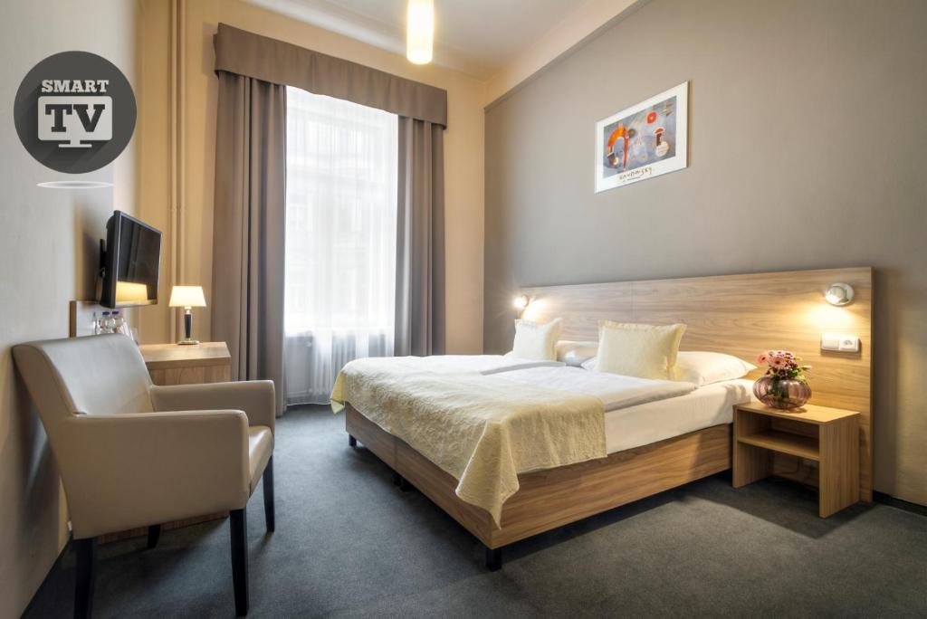 une chambre d'hôtel avec un lit et une chaise dans l'établissement Atlantic Hotel, à Prague