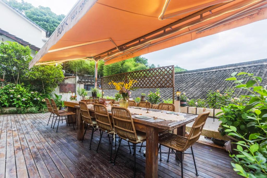 a wooden table with chairs and an umbrella on a deck at Boke Hotel Xihu in Hangzhou