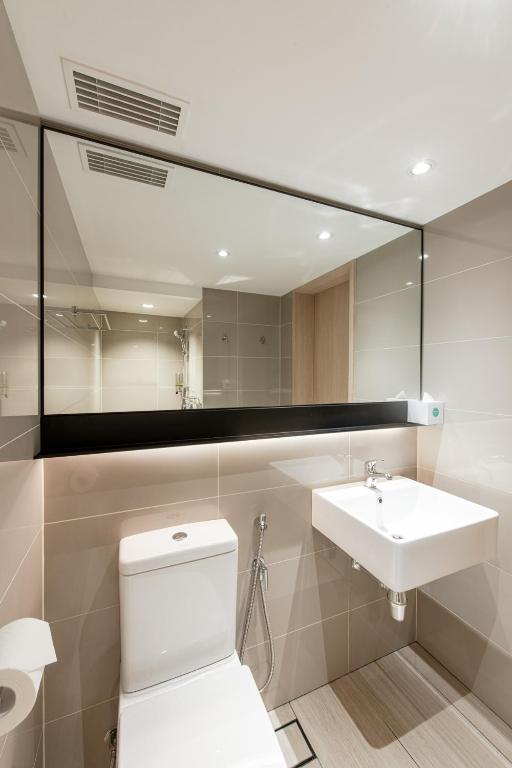 a bathroom with a sink and a toilet and a mirror at Komune Living in Kuala Lumpur