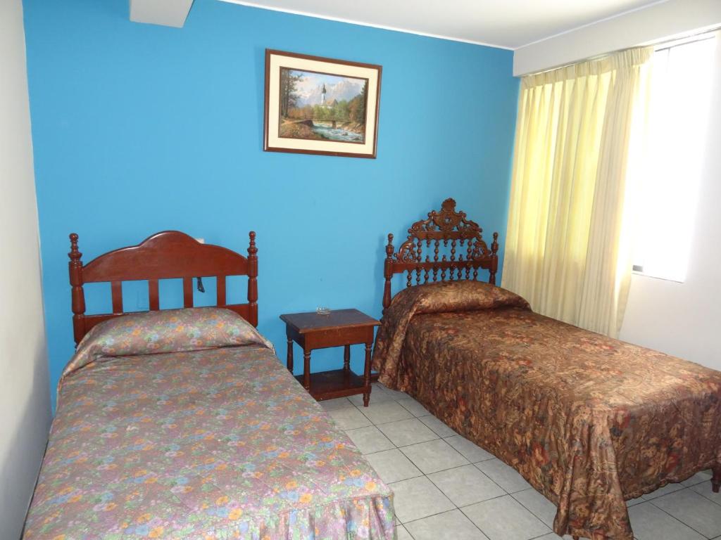 a bedroom with two beds and a blue wall at Hotel Nova in Lima