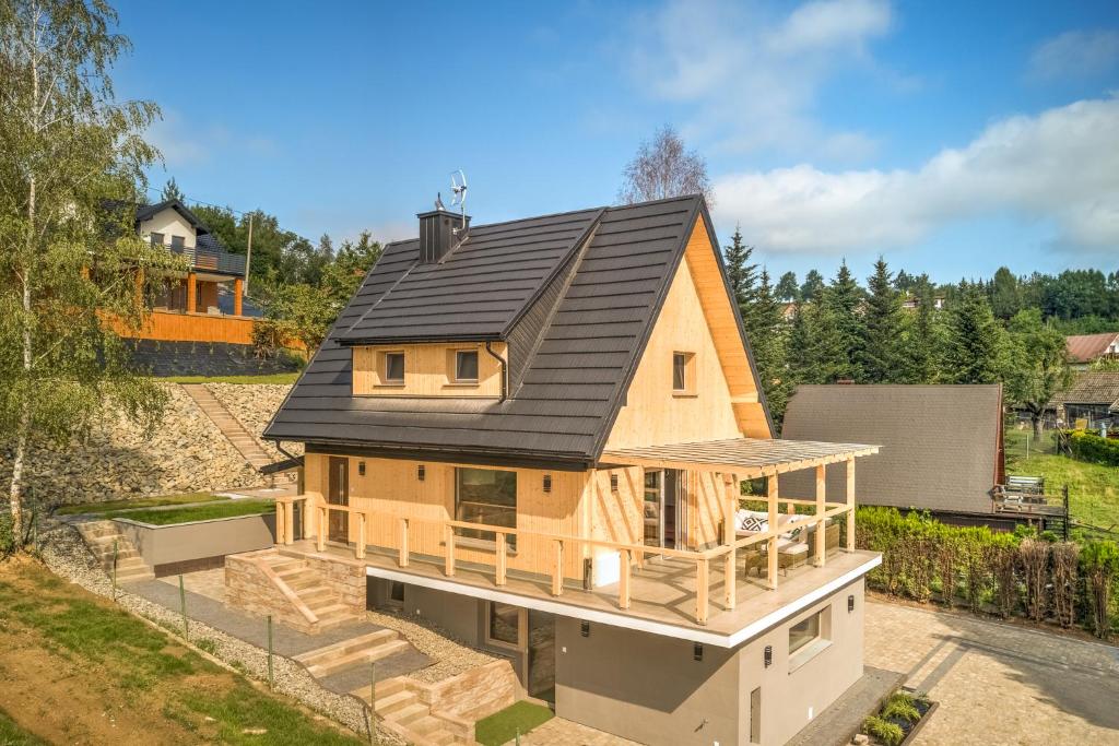una casa con un tetto nero sopra di Znamirowickachata SAUNA JACUZZI SPA a Znamirowice