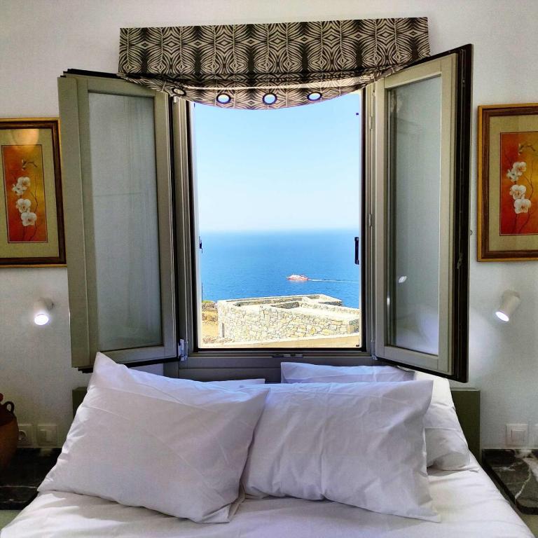 ein Bett mit einem großen Fenster und Blick auf das Meer in der Unterkunft Anerada sunset in Áno Meriá