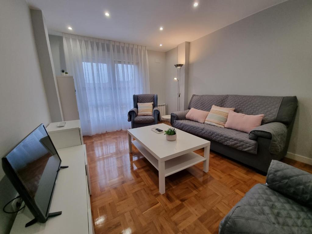 een woonkamer met een bank en een tafel bij 153A 3 dormitorios Barrio de La Arena con parking in Gijón