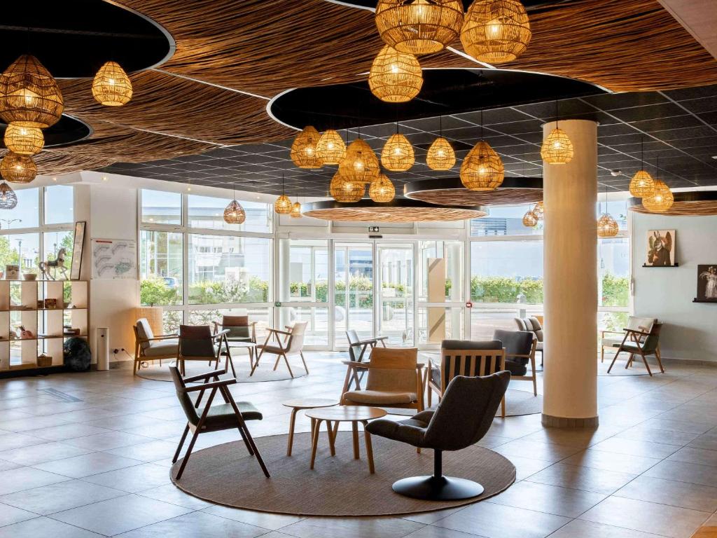 a lobby with chairs and tables and lights at Mercure Compiègne Sud in Compiègne