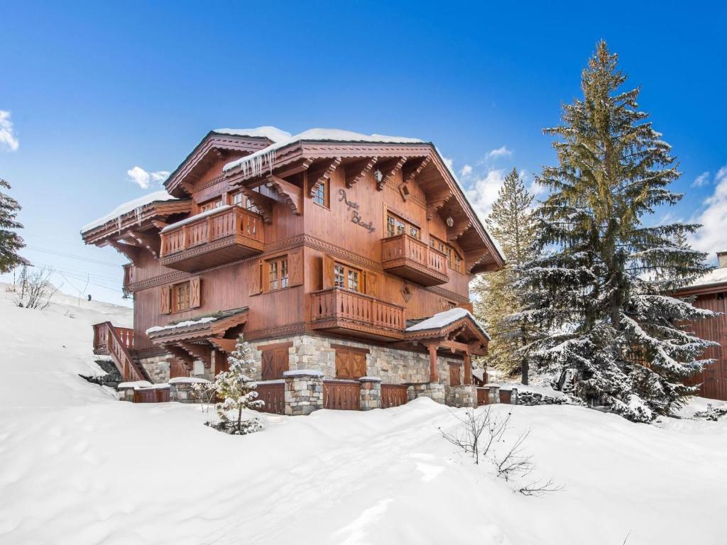 une grande maison en bois dans la neige avec un arbre dans l'établissement Chalet Courchevel 1650, 7 pièces, 12 personnes - FR-1-563-17, à Courchevel