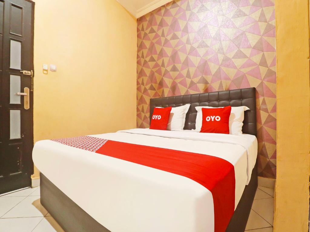 a bedroom with a bed with two red pillows at OYO 90492 Papi Inn Guesthouse in Palangkaraya
