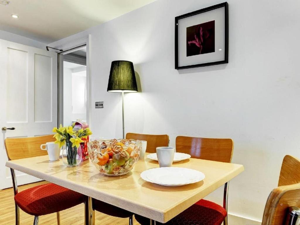 a dining room table with chairs and a table with a bowl of fruit at Bedford Place Hostels in London