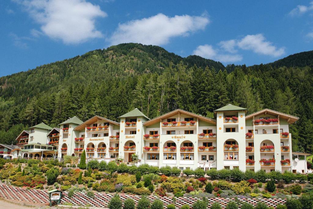 a large hotel with a mountain in the background at Hotel Saxl in Campo di Trens