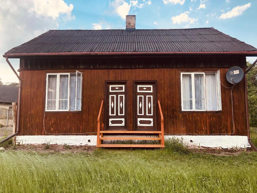 a small wooden house with a porch in the grass at Agroturystyka Mokre in Barkowice