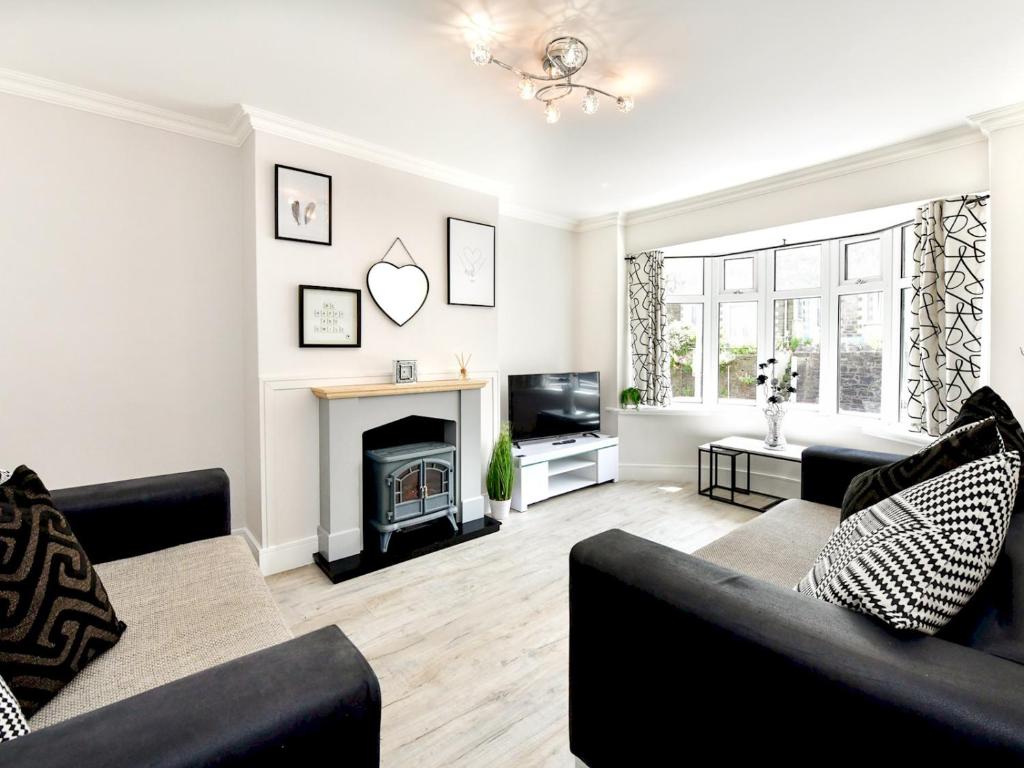 a living room with two black couches and a fireplace at Pass the Keys Newly refurbished modern bungalow - Pets Welcome in Swansea
