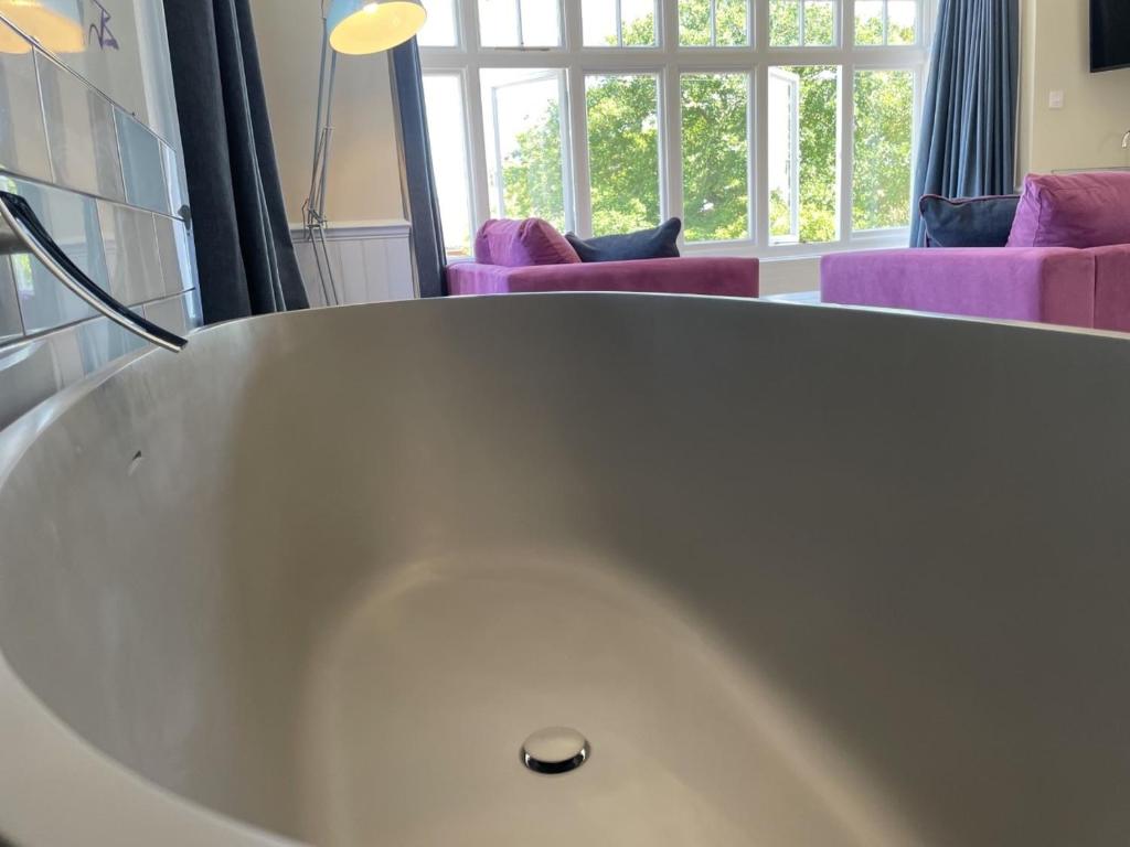 a white bath tub in a room with purple furniture at The Randolph Hotel in Southwold