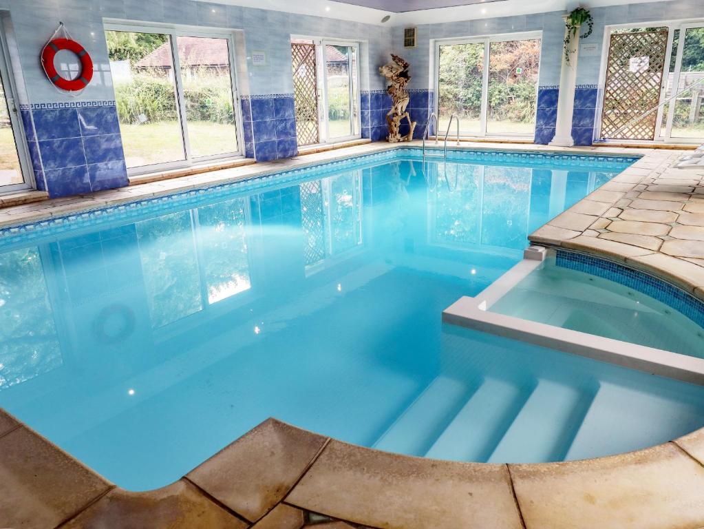 a large pool with blue water in a house at The Orchard in Rye