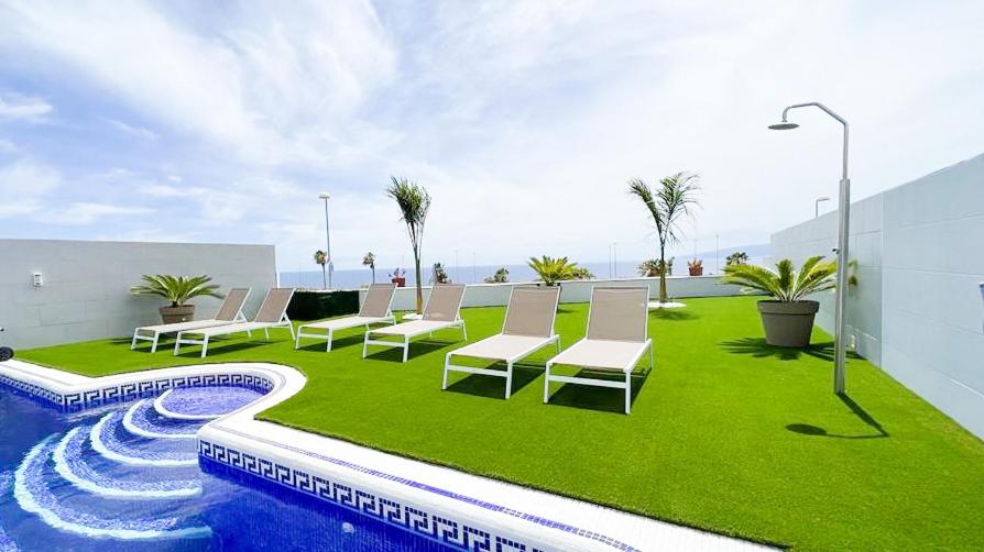 阿德赫的住宿－Villa Elisabetta, Luxury Villa with Heated Pool Ocean View in Adeje, Tenerife，一组椅子坐在游泳池旁的草坪上