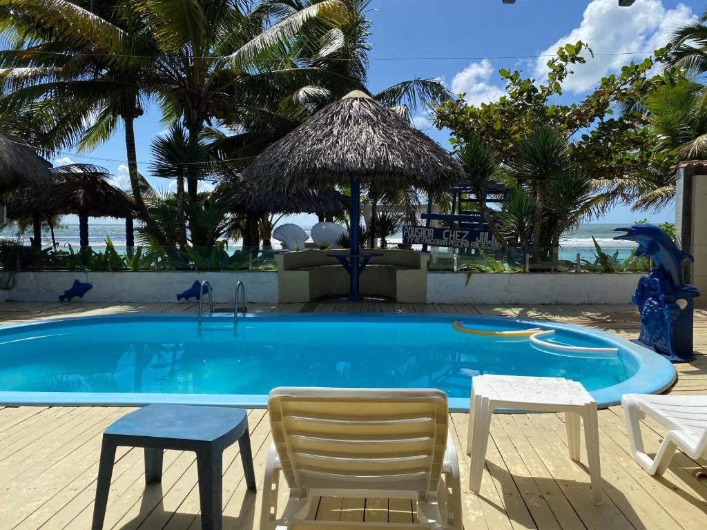 a swimming pool with two chairs and a table and chairs at Pousada Chez Julie in Pontal do Peba