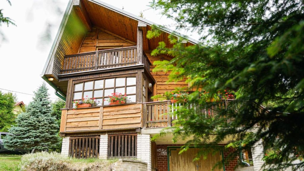 a wooden house with a balcony and flowers on it at CHATA U VINCENTA s fínskou saunou a altánkom in Hnilčík