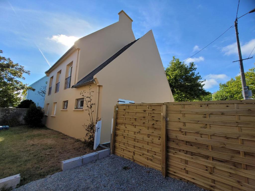 une maison blanche avec une clôture en bois devant elle dans l'établissement Maison de ville avec 4 grandes chambres, à Brest