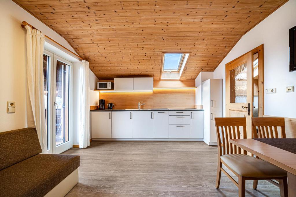 cocina con armarios blancos y techo de madera en Rasnerhof Ferienwohnung Panorama, en Lagundo