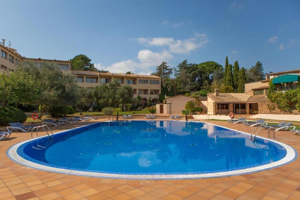 uma grande piscina azul num resort em Villa en el Golf Costa Brava a 5 min de la playa em Santa Cristina d'Aro